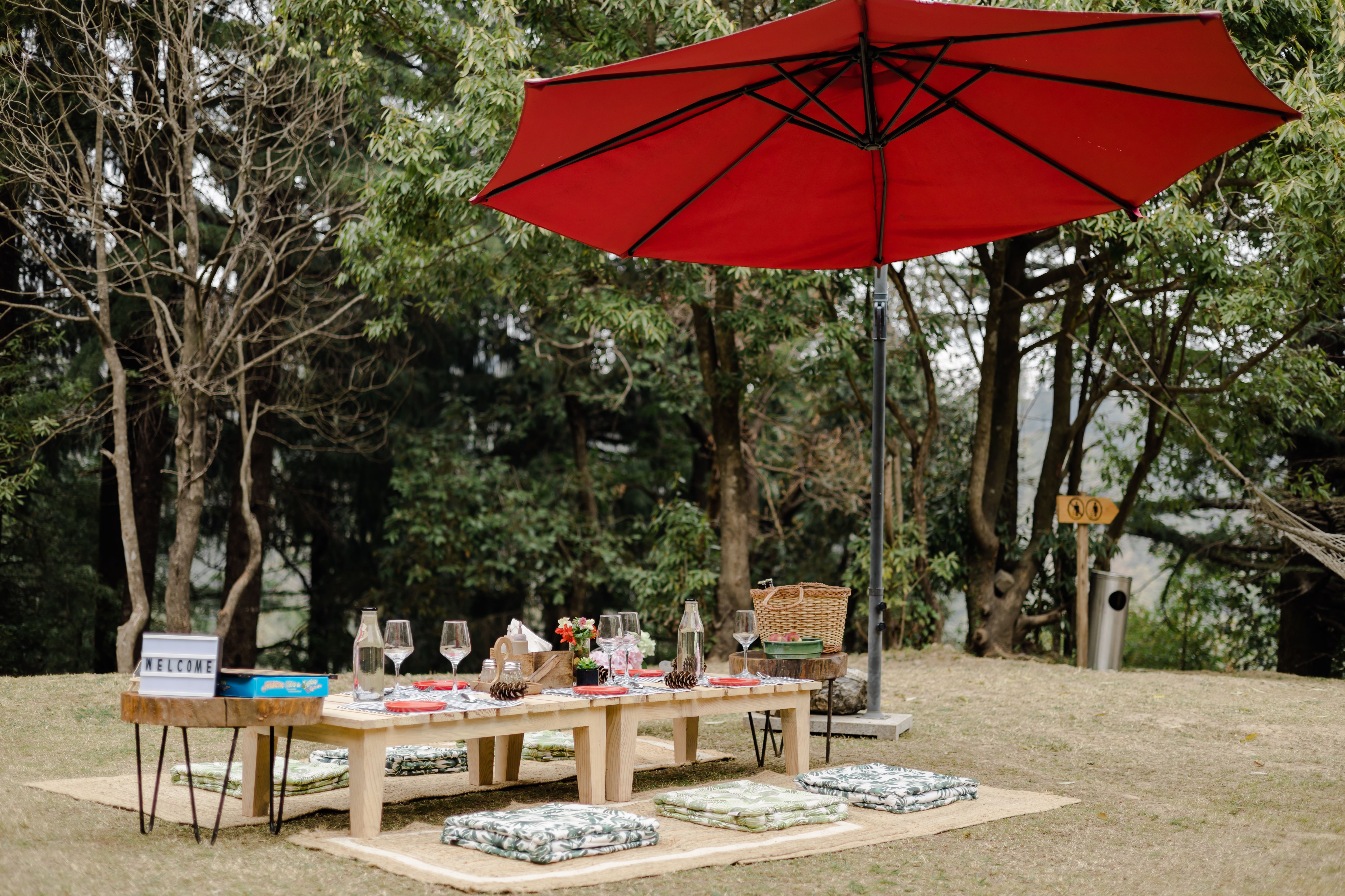 Complete lakeside picnic setup with sun umbrella, low table, cushion seating, wine glasses, and charcuterie board at Lake Merritt